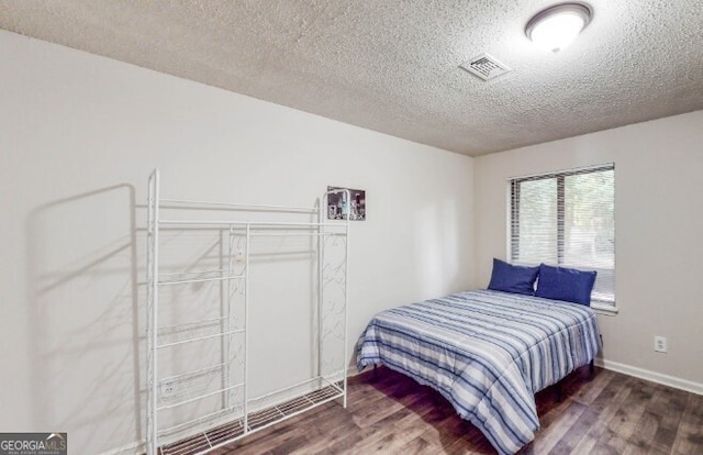 bedroom featuring dark hardwood / wood-style flooring and a textured ceiling