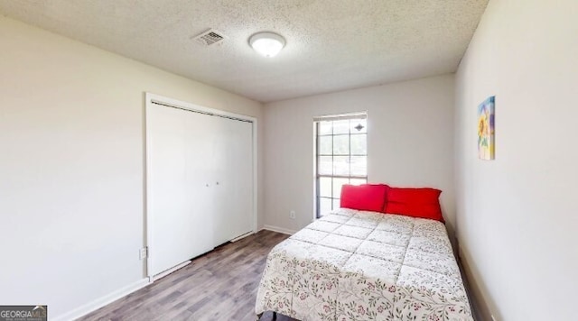 bedroom with a closet, light hardwood / wood-style floors, and a textured ceiling