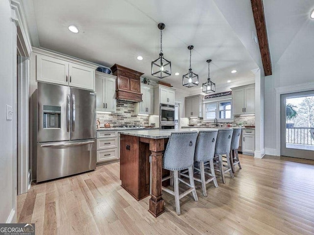 kitchen with a kitchen breakfast bar, light wood-type flooring, stainless steel appliances, pendant lighting, and a kitchen island