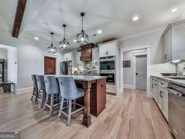 kitchen featuring tasteful backsplash, a center island, stainless steel appliances, and decorative light fixtures