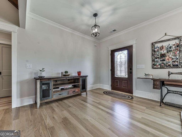 entryway with a notable chandelier, light wood-type flooring, and crown molding