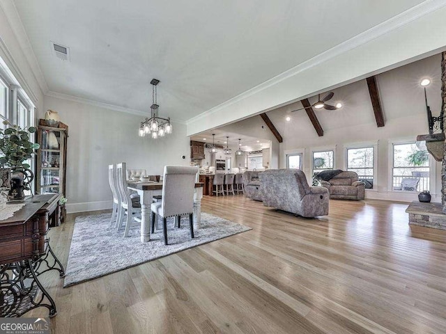 dining area featuring a notable chandelier, lofted ceiling with beams, light wood-type flooring, and crown molding