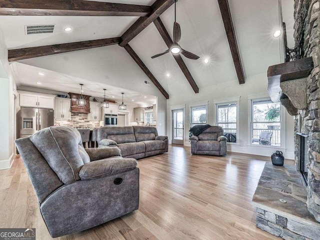 living room with high vaulted ceiling, light hardwood / wood-style flooring, ceiling fan, a fireplace, and beamed ceiling