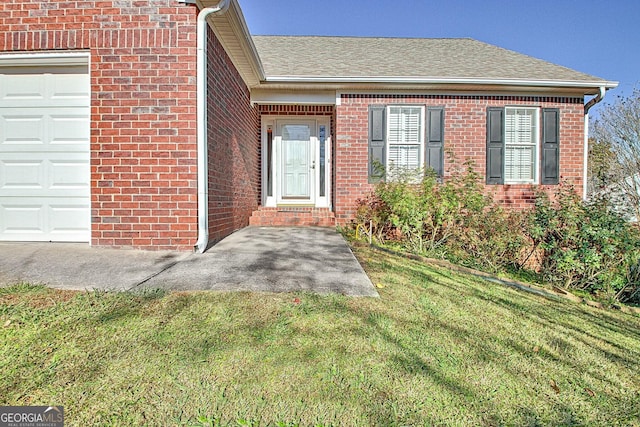 view of exterior entry with a lawn and a garage