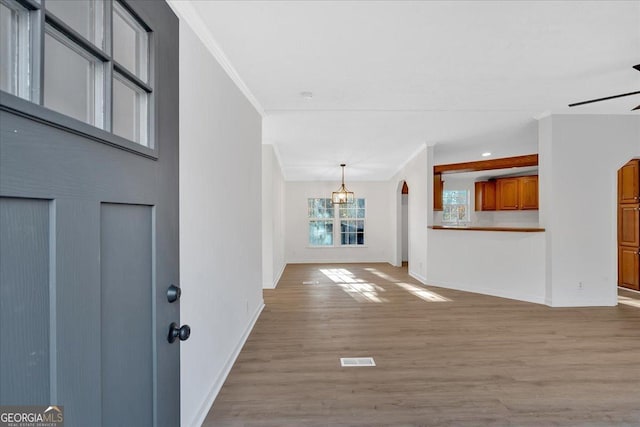 entrance foyer featuring ornamental molding, ceiling fan with notable chandelier, and light wood-type flooring