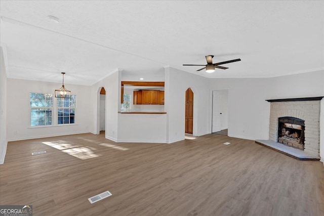 unfurnished living room with a fireplace, light hardwood / wood-style floors, and ceiling fan with notable chandelier