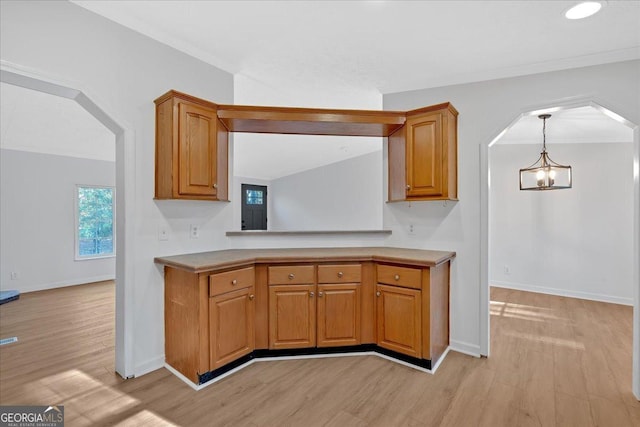 kitchen featuring a notable chandelier, crown molding, decorative light fixtures, and light hardwood / wood-style flooring