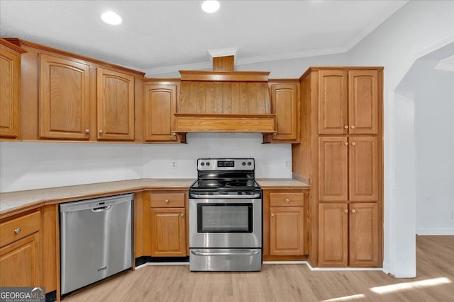 kitchen featuring crown molding, lofted ceiling, stainless steel appliances, and light hardwood / wood-style flooring