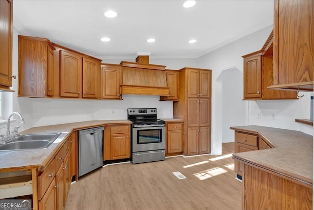 kitchen with ornamental molding, sink, appliances with stainless steel finishes, and light hardwood / wood-style flooring