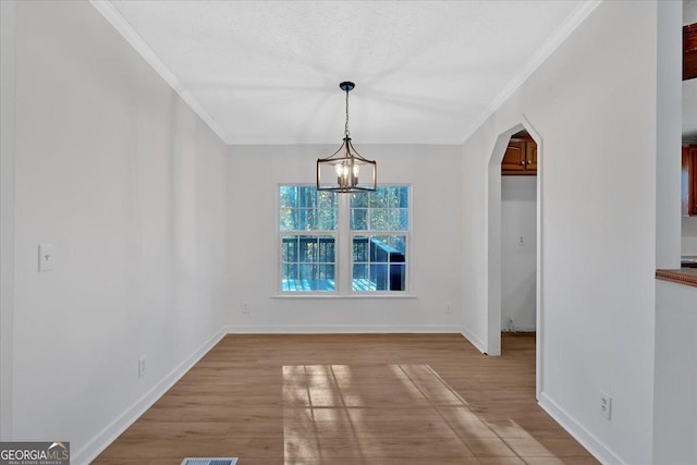 unfurnished dining area with a chandelier, light hardwood / wood-style floors, and ornamental molding