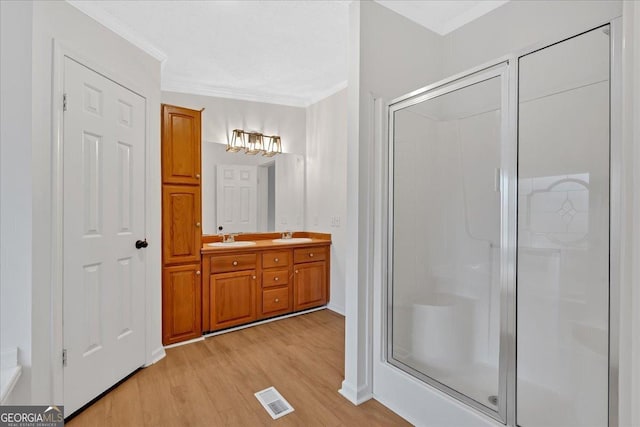 bathroom with crown molding, hardwood / wood-style floors, vanity, and walk in shower