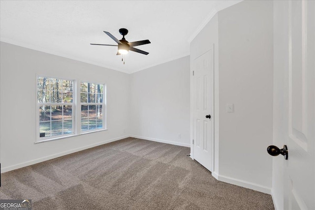 empty room featuring ceiling fan, light colored carpet, and crown molding