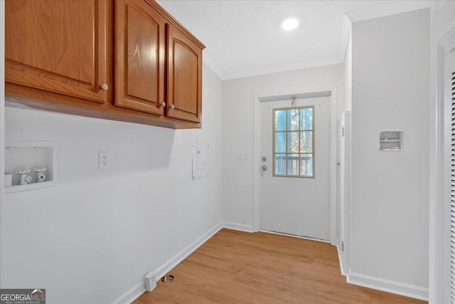 washroom featuring washer hookup, cabinets, light wood-type flooring, and ornamental molding