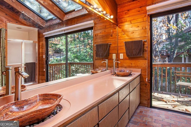 bathroom featuring vanity, wood walls, and lofted ceiling with skylight