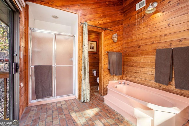 bathroom featuring shower with separate bathtub, toilet, and wooden walls