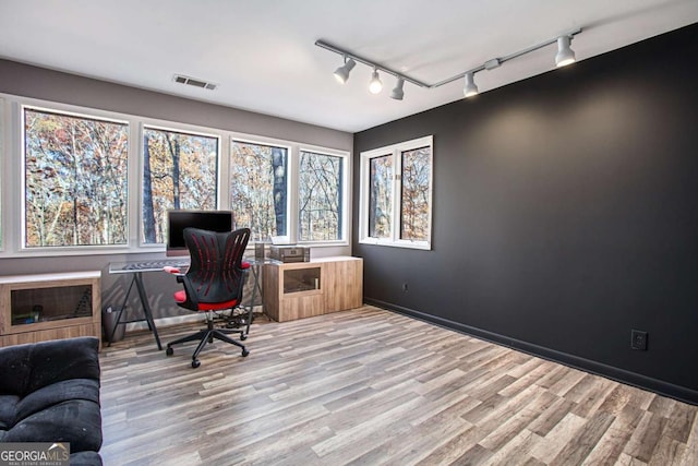 office with light hardwood / wood-style floors and track lighting