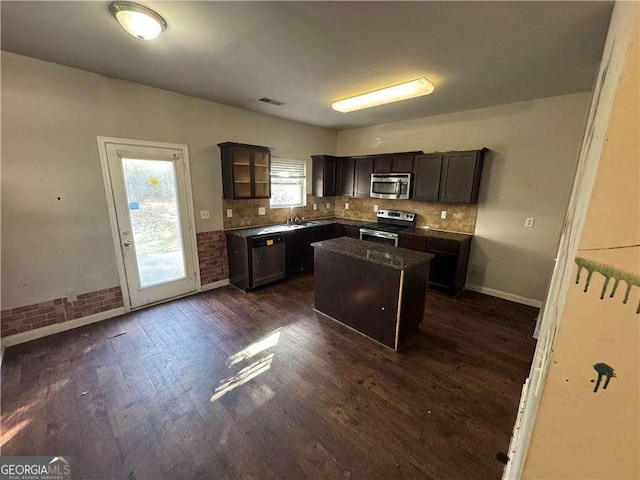 kitchen with dark brown cabinets, a kitchen island, stainless steel appliances, and dark wood-type flooring