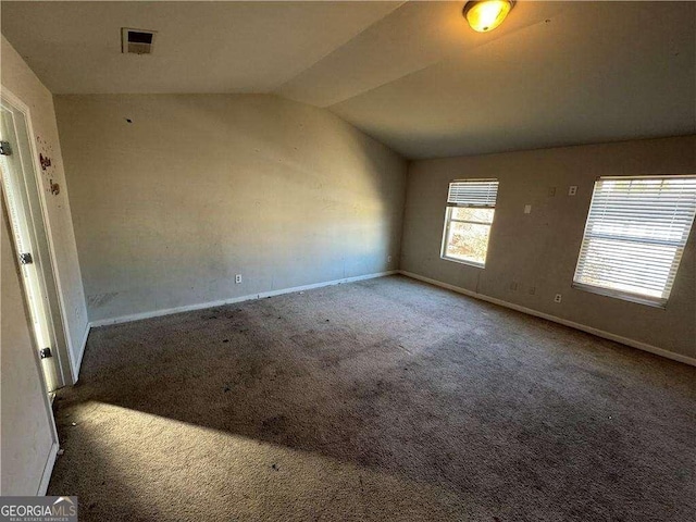 carpeted empty room featuring lofted ceiling