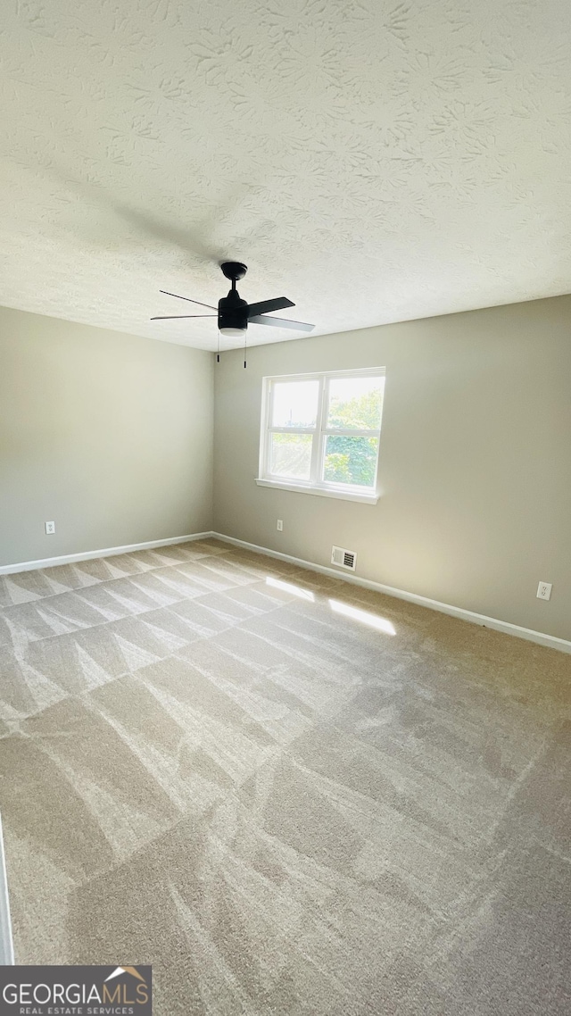 carpeted spare room with a textured ceiling and ceiling fan