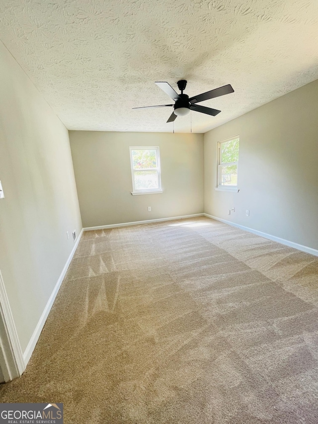 carpeted empty room featuring ceiling fan and a textured ceiling