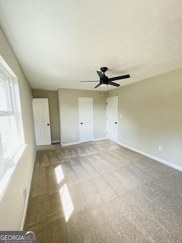 unfurnished bedroom featuring carpet, a textured ceiling, and ceiling fan