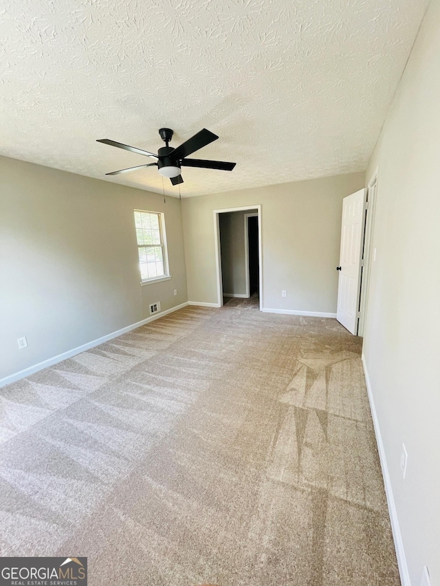 carpeted spare room with ceiling fan and a textured ceiling