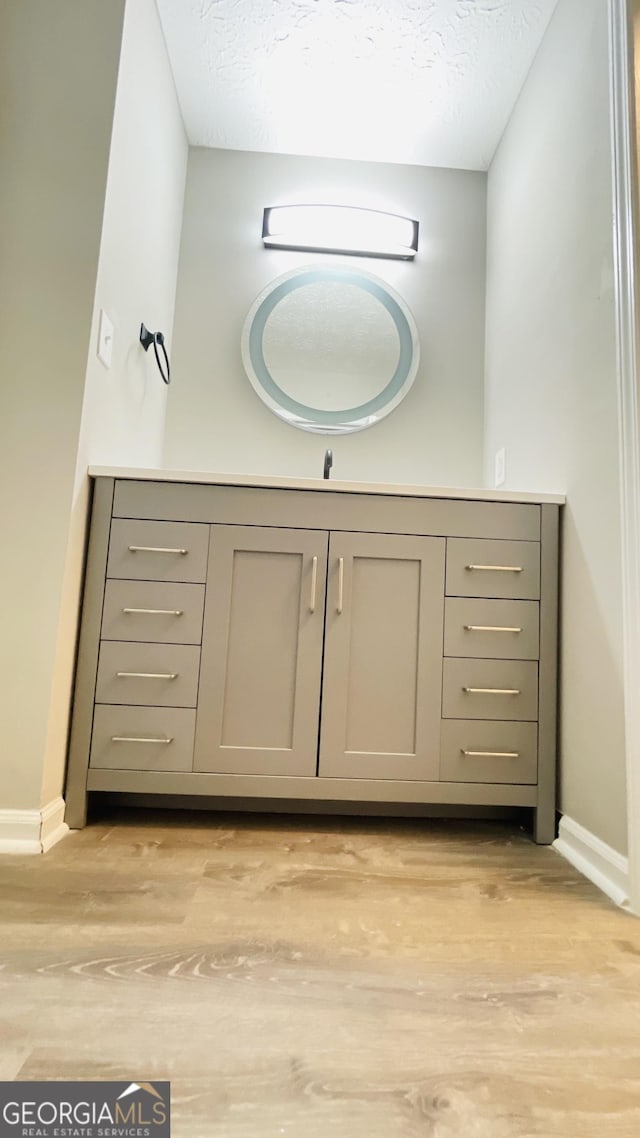 bathroom featuring vanity, wood-type flooring, and a textured ceiling