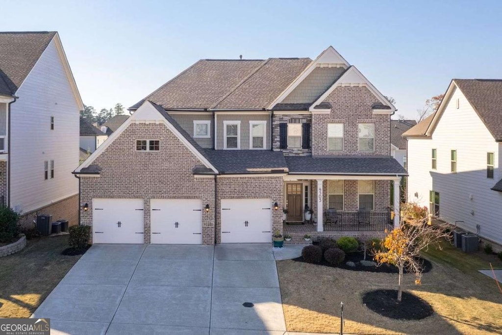 view of front of home with central air condition unit, covered porch, a front yard, and a garage