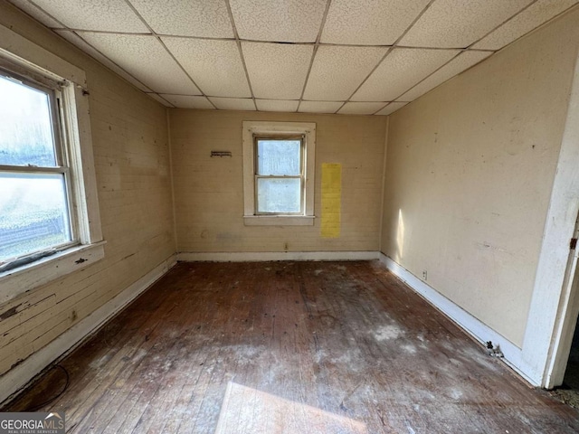 spare room with a paneled ceiling, plenty of natural light, and dark wood-type flooring