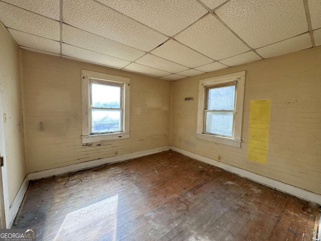 spare room featuring hardwood / wood-style flooring and a drop ceiling