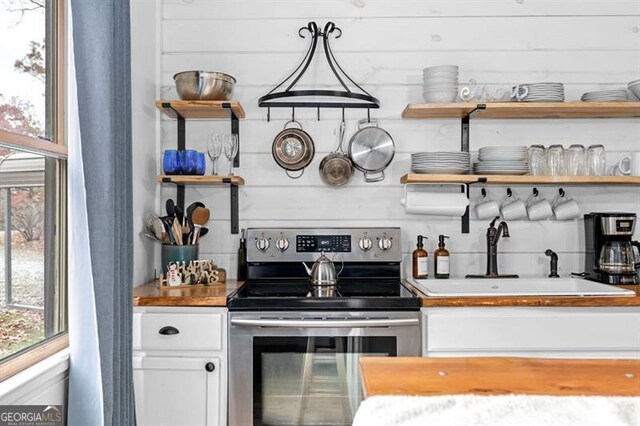 kitchen with pendant lighting, sink, white cabinetry, and electric stove