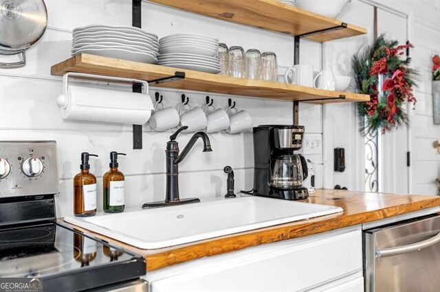 kitchen with dishwasher, stove, white cabinets, and sink