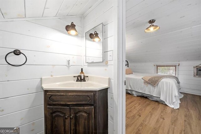 bathroom with hardwood / wood-style floors, vanity, wood walls, wooden ceiling, and vaulted ceiling