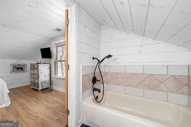 bathroom featuring wood walls, wood-type flooring,  shower combination, lofted ceiling, and wood ceiling