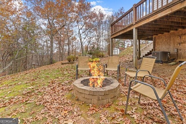 view of yard featuring a deck, an outdoor fire pit, and central AC