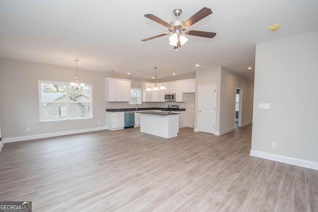 kitchen with light wood-type flooring, stainless steel appliances, decorative light fixtures, white cabinets, and a kitchen island