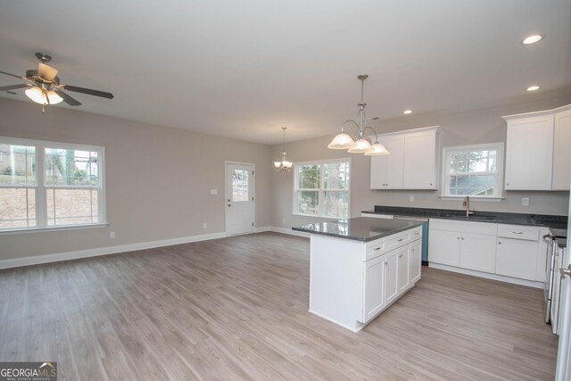 kitchen with white cabinetry, sink, hanging light fixtures, stainless steel appliances, and dark stone counters