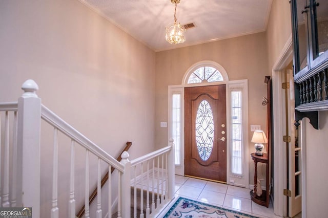 entryway with light tile patterned flooring, crown molding, and an inviting chandelier