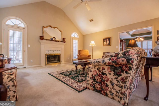 carpeted living room featuring ceiling fan with notable chandelier and vaulted ceiling