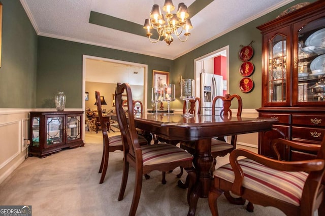 carpeted dining area with a notable chandelier, ornamental molding, and a textured ceiling