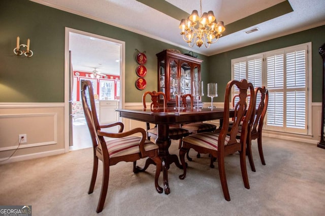 carpeted dining space featuring a chandelier, a textured ceiling, and ornamental molding