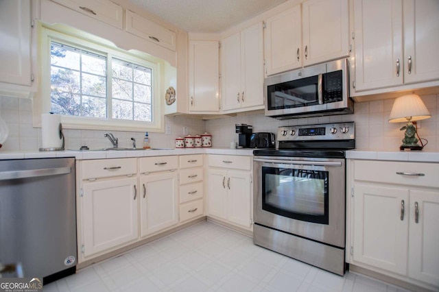 kitchen featuring white cabinets, decorative backsplash, sink, and stainless steel appliances