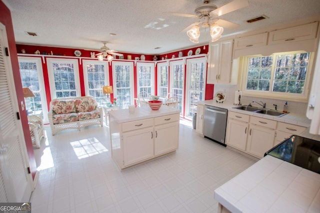 kitchen featuring tile countertops, dishwasher, plenty of natural light, and sink