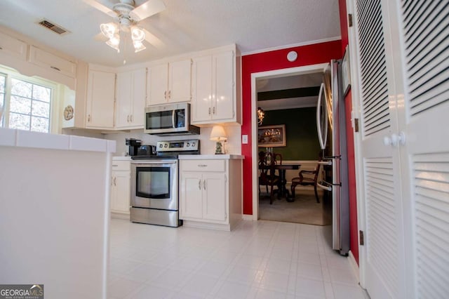 kitchen featuring ceiling fan, white cabinets, stainless steel appliances, and a textured ceiling