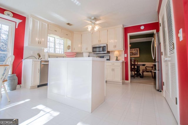 kitchen featuring white cabinetry, a healthy amount of sunlight, ceiling fan, and stainless steel appliances