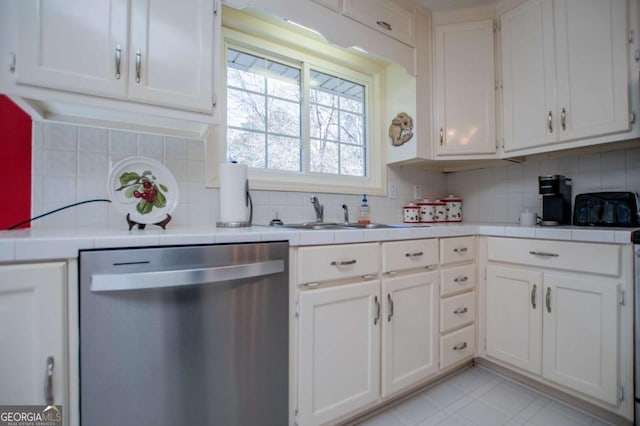 kitchen with stainless steel dishwasher, tile counters, white cabinetry, and tasteful backsplash