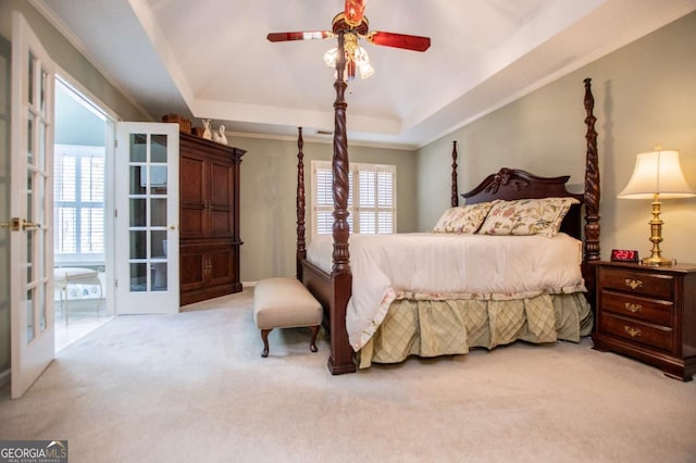 carpeted bedroom with ceiling fan, a raised ceiling, crown molding, and french doors