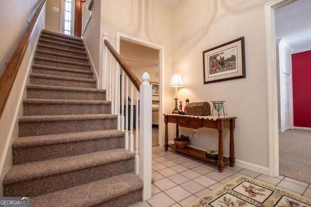 stairway with tile patterned floors and ornamental molding