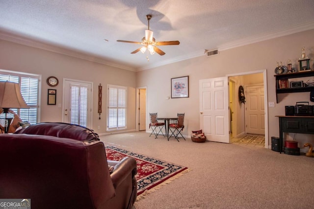 living room featuring light carpet, ceiling fan, a textured ceiling, and ornamental molding