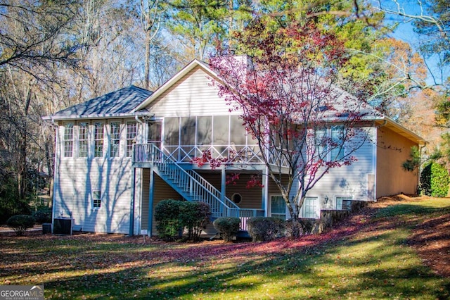 rear view of property featuring a sunroom, a yard, and central AC